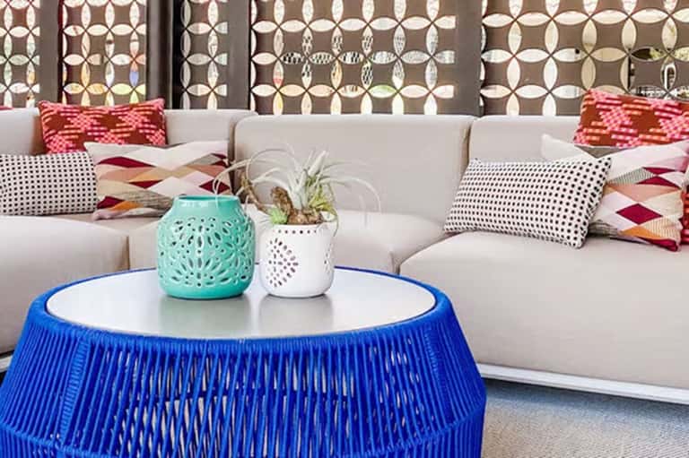 Modern lounge seating with cream sofa, colorful patterned pillows, and blue woven coffee table