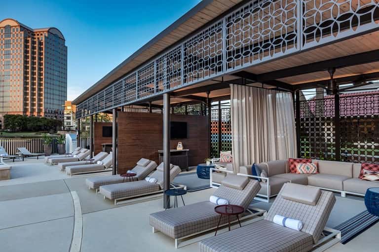 Modern rooftop lounge with geometric pergola, loungers, and urban skyline views