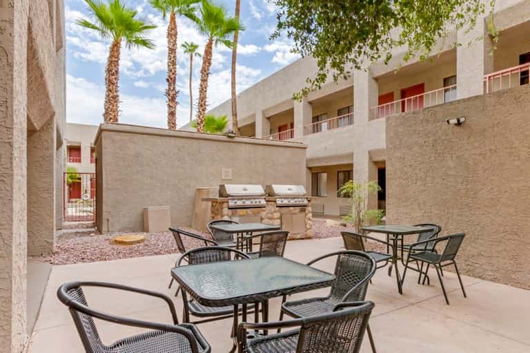 Courtyard with palm trees, patio seating, built-in grills, and multi-story residential building
