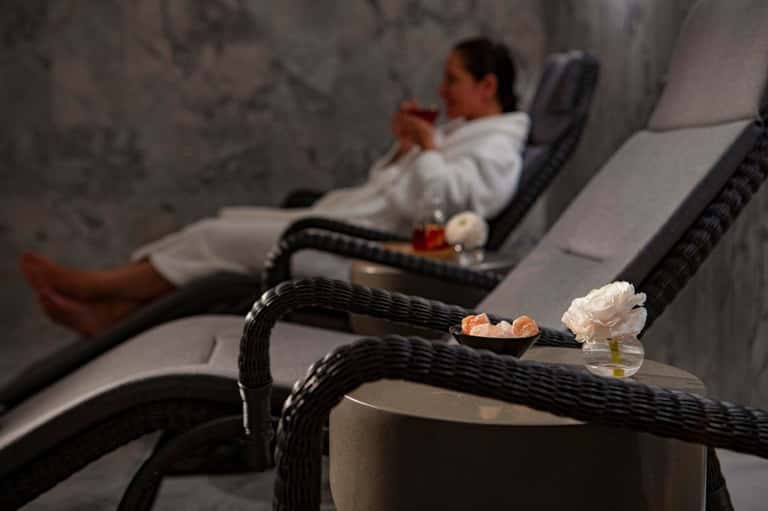 Spa lounge with reclining chairs, white flowers, and aromatherapy candles