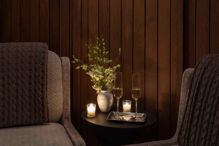 Intimate spa seating nook with textured chairs, fresh flowers, and ambient candlelight