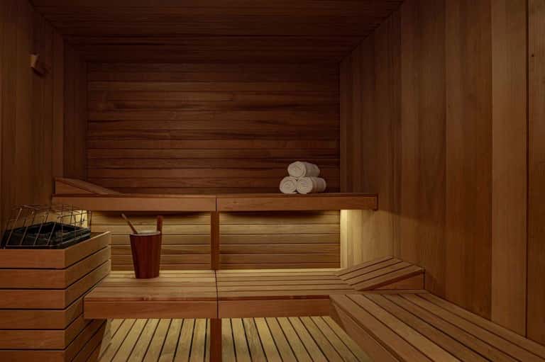 Wooden sauna interior with benches, rolled towels, and ambient lighting