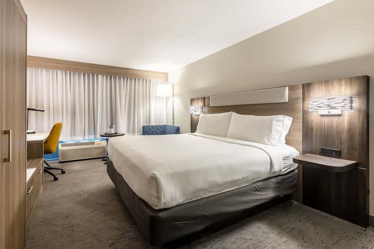 Modern hotel bedroom with king bed, work desk, and contemporary decor