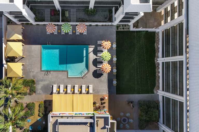 Aerial view of modern resort courtyard with turquoise pool and colorful umbrellas