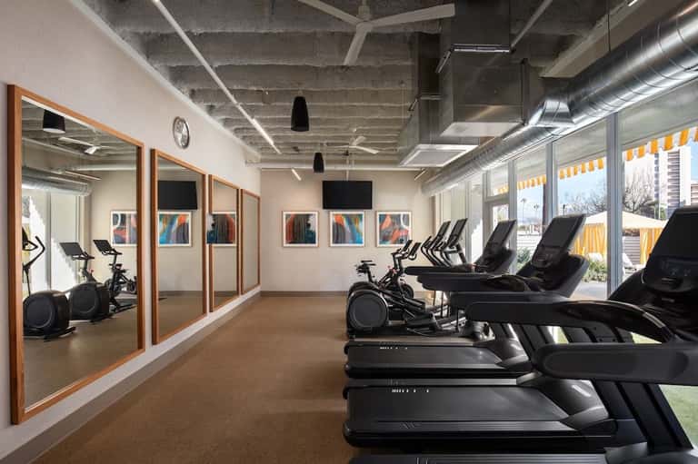 Bright fitness studio with treadmills, exercise bikes, and glass partition walls