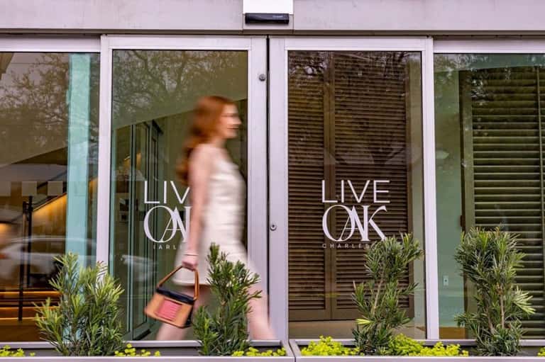 Live Oak Charles hotel entrance with frosted glass doors and green landscaping at street level