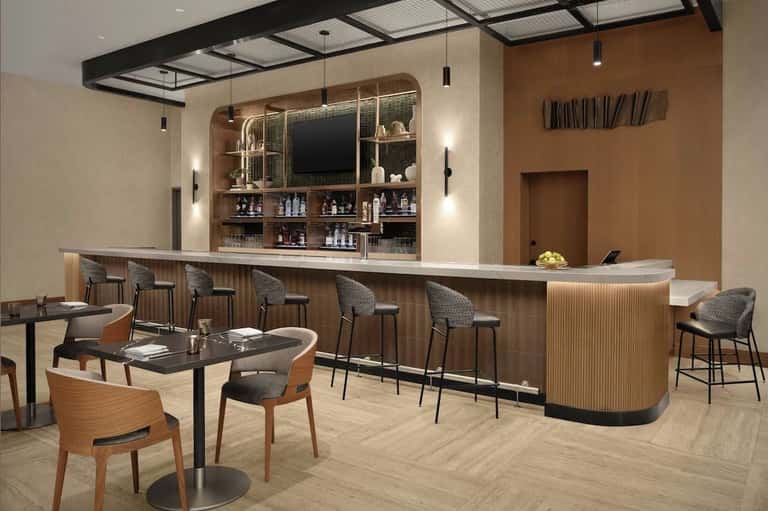 Modern lounge bar with wooden bar counter, seating area, and illuminated shelving