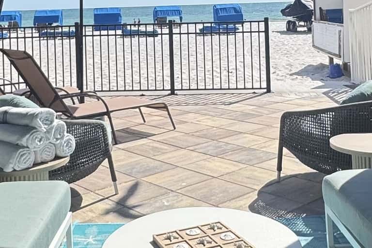 Beachfront deck with lounge chairs, rolled towels, and ocean view behind metal railing