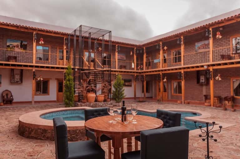 Colonial-style courtyard with central pool, wooden railings, brick buildings, and wooden table