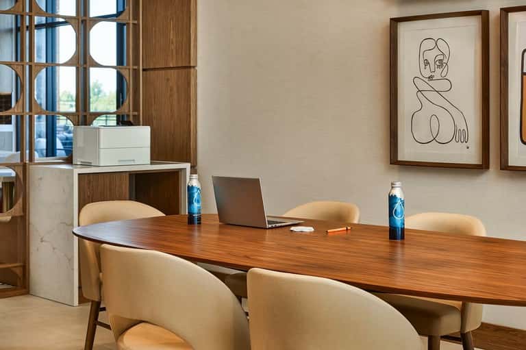 Contemporary conference room with wooden table, cream chairs, geometric window frames, and minimalist wall art