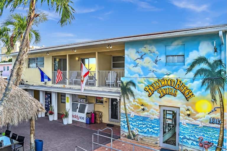 Hollywood Beach Hotel exterior with mural art, palm tree, and two-story building with flags