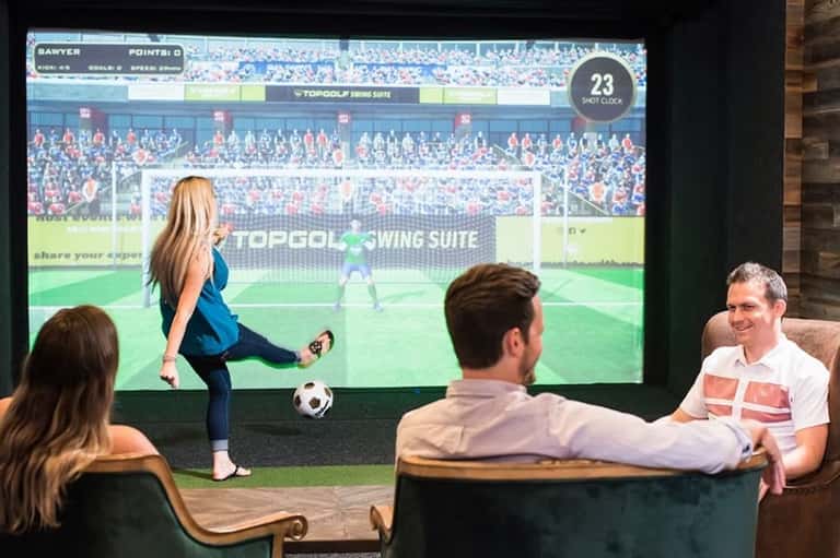 Group playing interactive soccer game on large screen in modern lounge setting