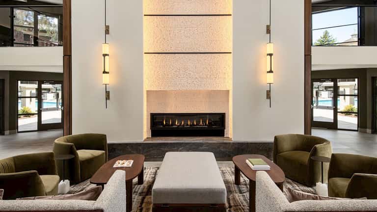 Modern hotel lobby with fireplace, contemporary lighting, and earth-tone seating