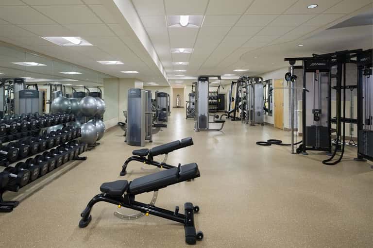 Spacious gym with dumbbells, weight machines, stability balls, and mirrored walls for strength training