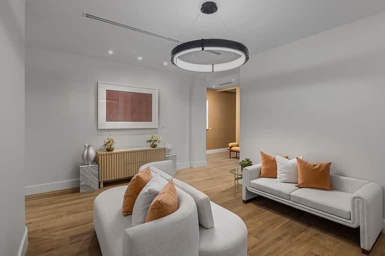 Modern spa lounge with white curved seating, wooden accents, and contemporary circular pendant lighting