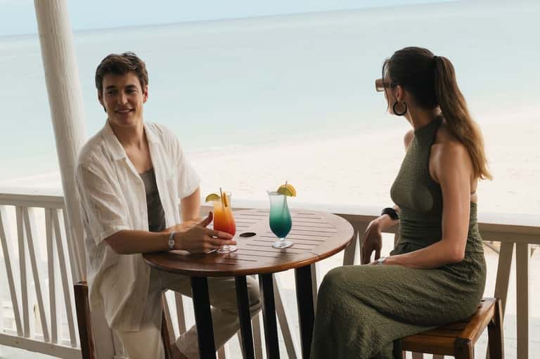 Couple enjoying colorful tropical cocktails on an oceanview balcony at sunset