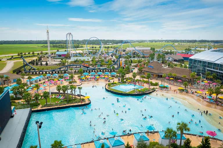 Aerial view of a large water park with wave pool, lazy river, roller coasters, and green grounds