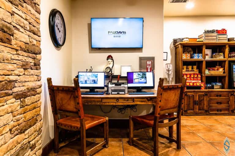 Business center workspace with dual monitors, wooden desk, and stone accent wall