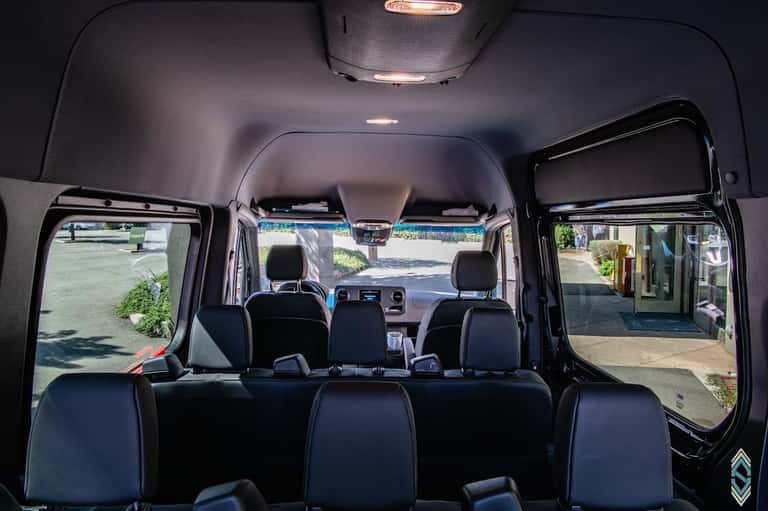 Van interior with black seating, windows, and front dashboard view