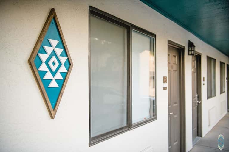 Hotel hallway with turquoise geometric diamond wall art and multiple guest room doors