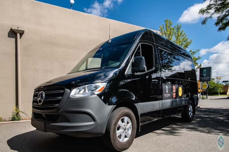 Black Mercedes-Benz passenger van parked outside modern building in daylight