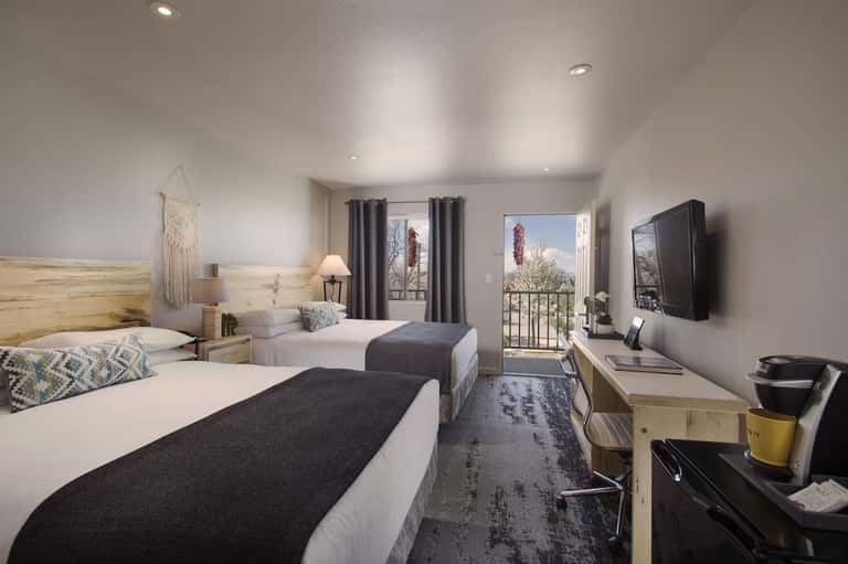 Hotel room with two queen beds, wooden furniture, TV, balcony access, and contemporary décor