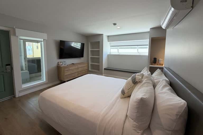 Master bedroom with king bed, TV, wooden dresser, ensuite bathroom, and sliding glass patio door