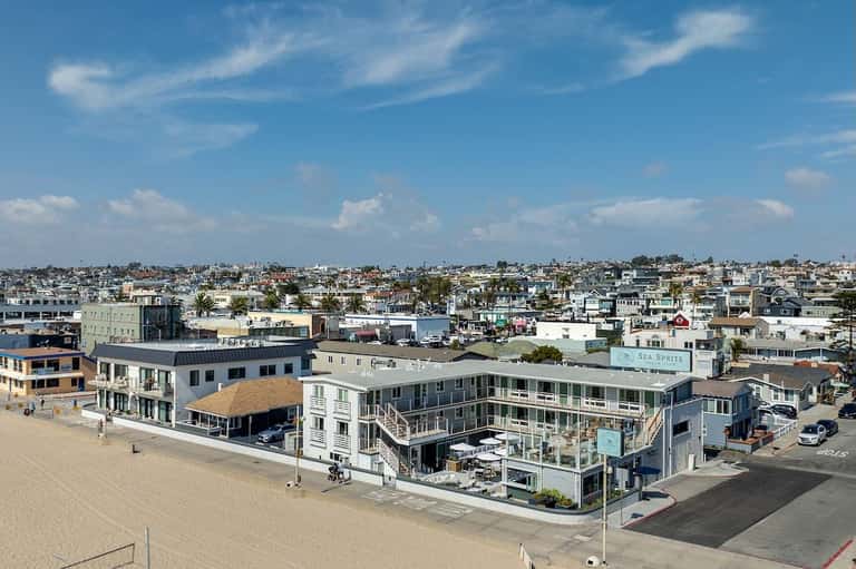 Aerial view of beachfront resort complex with multiple buildings, beach access, and surrounding neighborhood