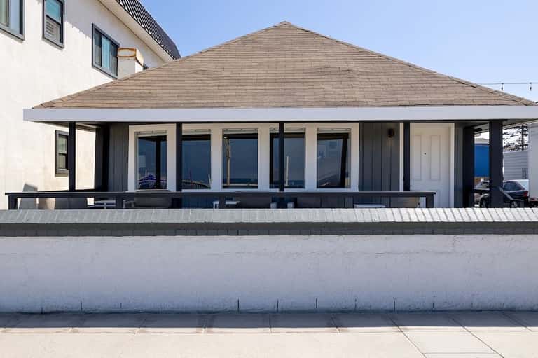 Modern beachfront pavilion with pitched roof, large windows, and ocean views