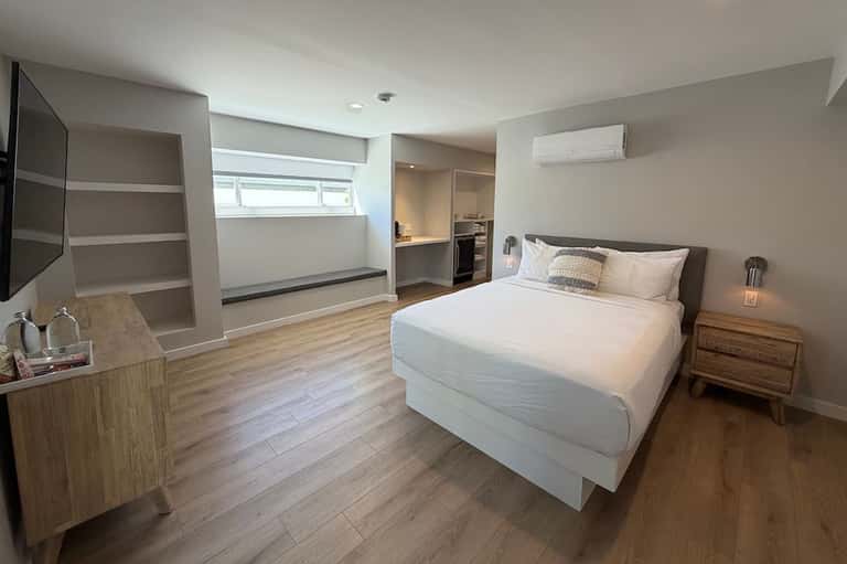 Spacious master bedroom with queen bed, wooden nightstands, and sitting area with shelving