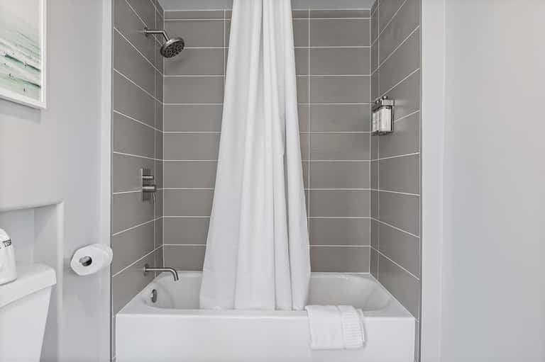 Contemporary bathroom with gray tile walls, white soaking tub, and shower enclosure