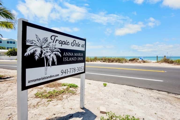 Tropic Isle at Anna Maria Island Inn sign on sandy roadside near beach access
