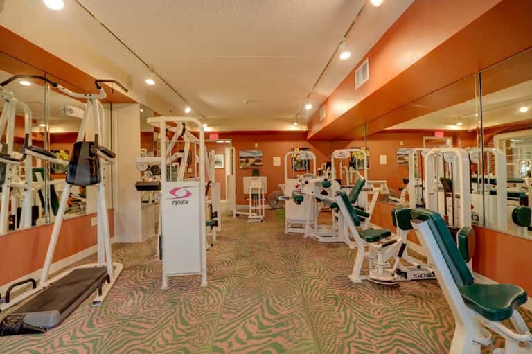 Modern fitness center with orange walls, Cybex exercise equipment, and mirrors