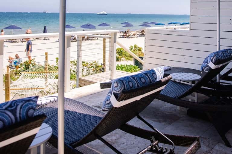 Beachfront lounge chairs with blue cushions overlooking the ocean and sandy beach