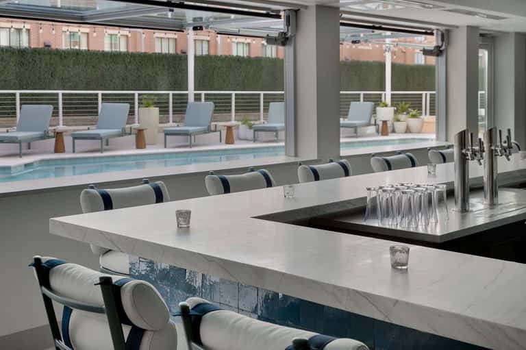 Indoor bar with view of outdoor pool through glass doors and lounge seating area