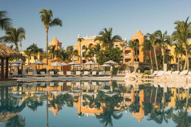 Ornate yellow colonial architecture with palm trees reflected in calm lagoon water