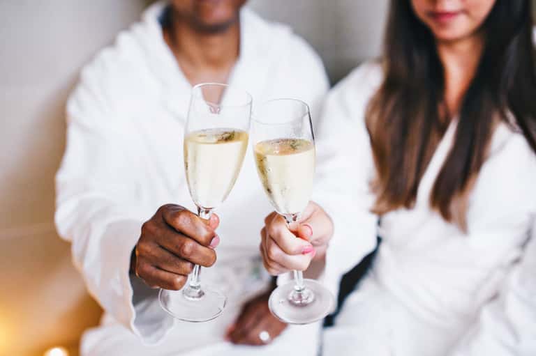 Couple in white clothing toasting with champagne glasses at an elegant celebration