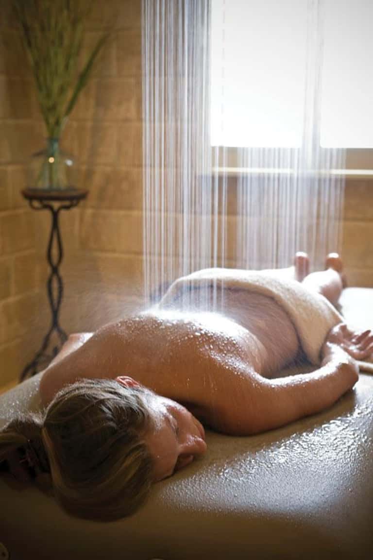 Close-up of a person receiving a massage treatment on their back with oils applied in a bright spa room