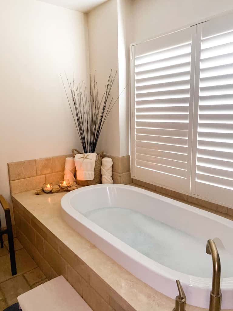 Soaking tub with modern fixtures, decorative candles, and plants in a contemporary spa bathroom