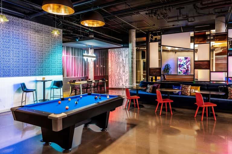 Game room with blue pool table, neon lighting, pink accent walls, and modern furniture