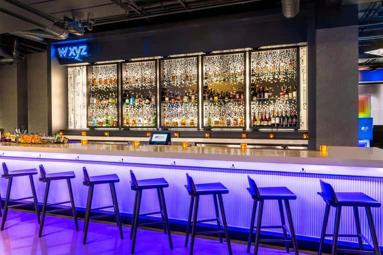 Contemporary bar counter with purple ambient lighting, bottle display, and neon signage