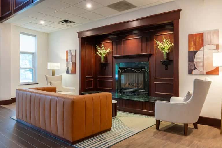 Elegant lounge with fireplace, orange sectional sofa, cream armchair, and modern artwork