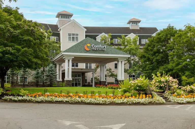 Comfort Inn & Suites exterior with columned entrance, manicured landscaping, and flower beds