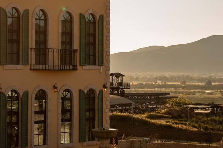 Terracotta colonial building with arched windows overlooking a valley landscape and mountains