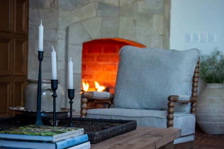Cozy fireplace lounge with gray upholstered chair, candles, and valley views through windows