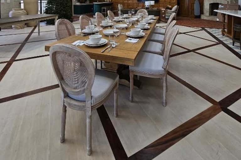 Formal dining room with long wooden table, upholstered chairs, and geometric wood flooring