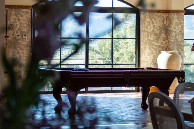 Game room with billiards table, patterned wallpaper, and large windows overlooking vineyard landscape