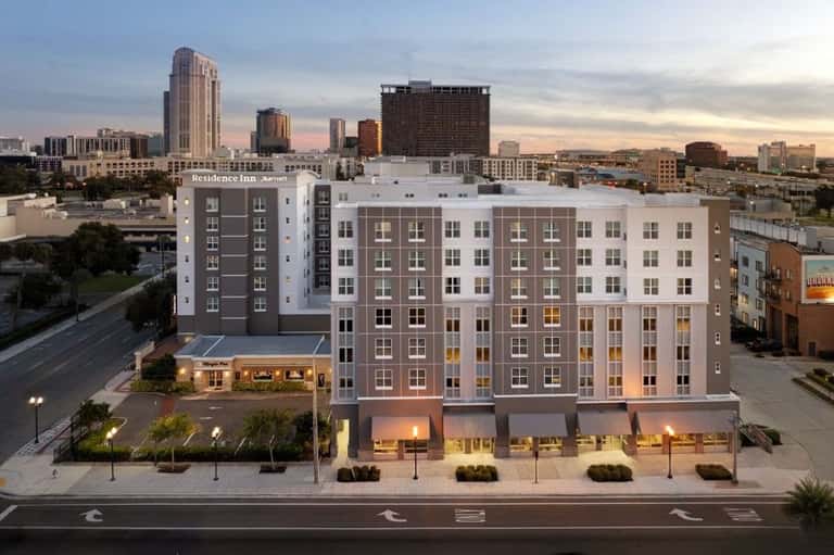 Multi-story residential building exterior at dusk with downtown cityscape in background
