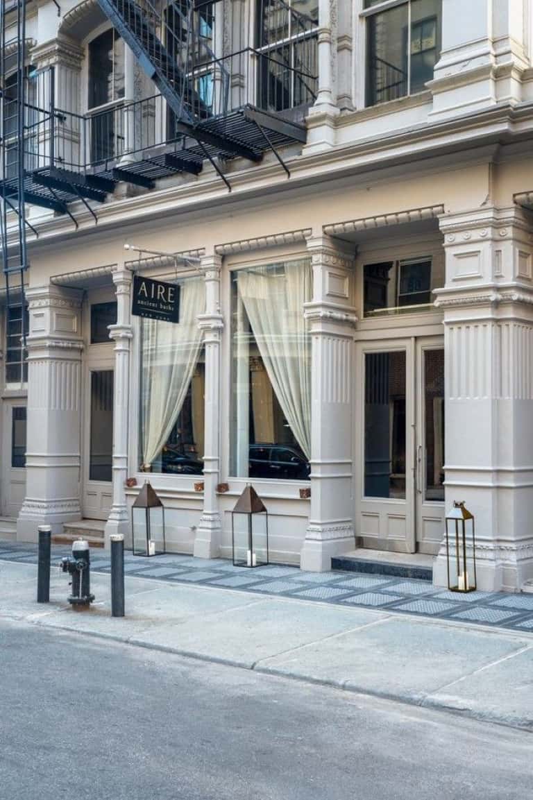 Elegant storefront entrance with classical white columns, cream curtains, and AIRE signage on city street