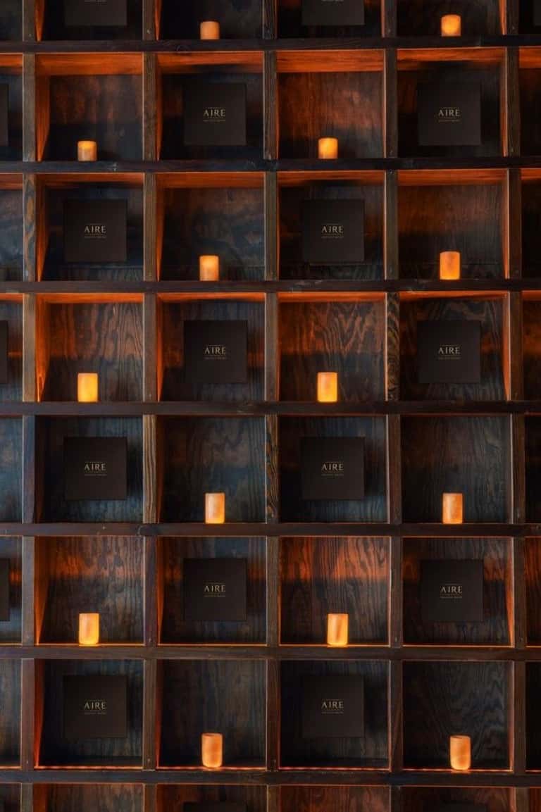 Wooden display shelves with AIRE branding, candles, and dark wood interior architecture with warm lighting